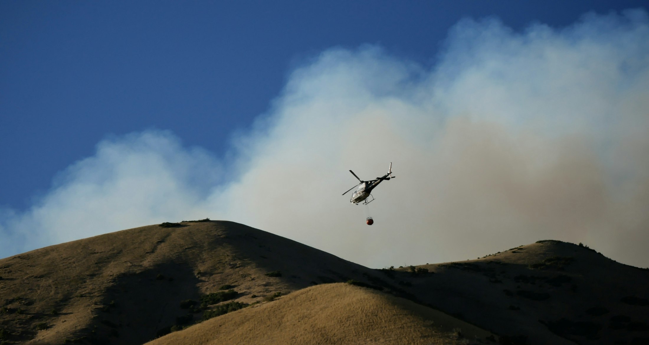 Helicóptero de extinción descargando agua sobre una ladera forestal durante la campaña de incendios